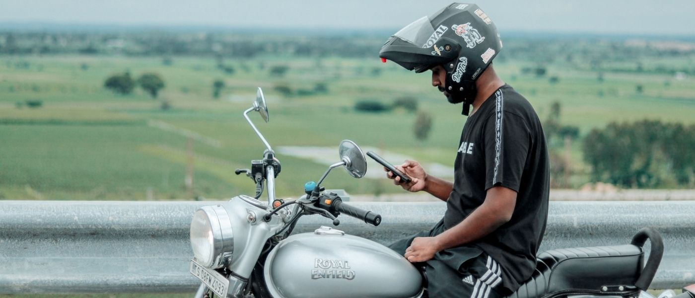 Photo d'un homme sur une moto qui tient son téléphone dans la main
